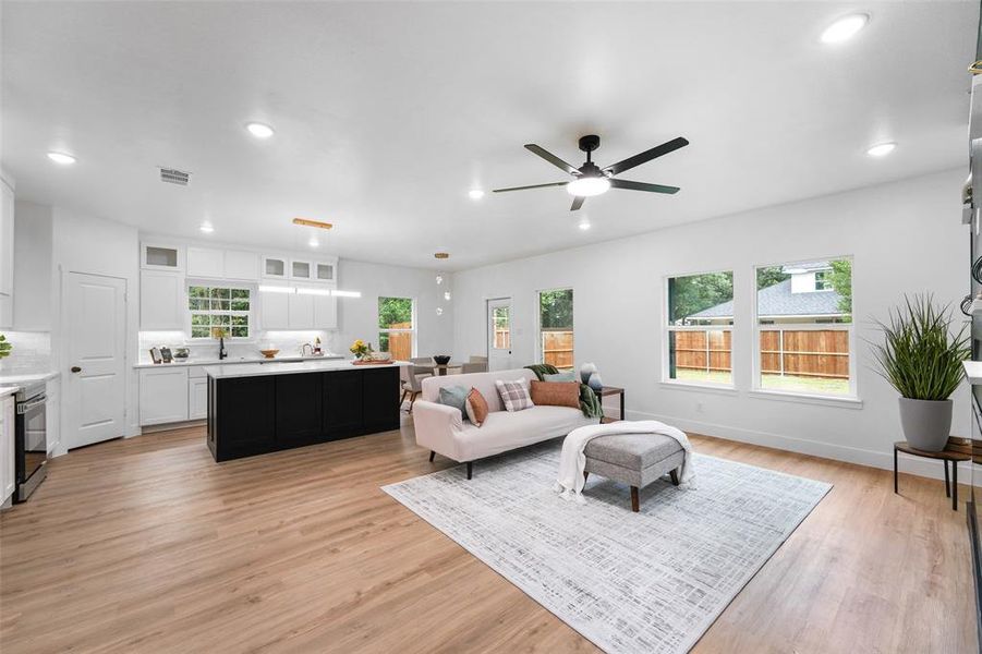 Open-concept living area featuring wood-finish flooring throughout, a modern ceiling fan, and recessed lighting Open-concept living area featuring wood-finish flooring throughout, a modern ceiling fan, and recessed lighting