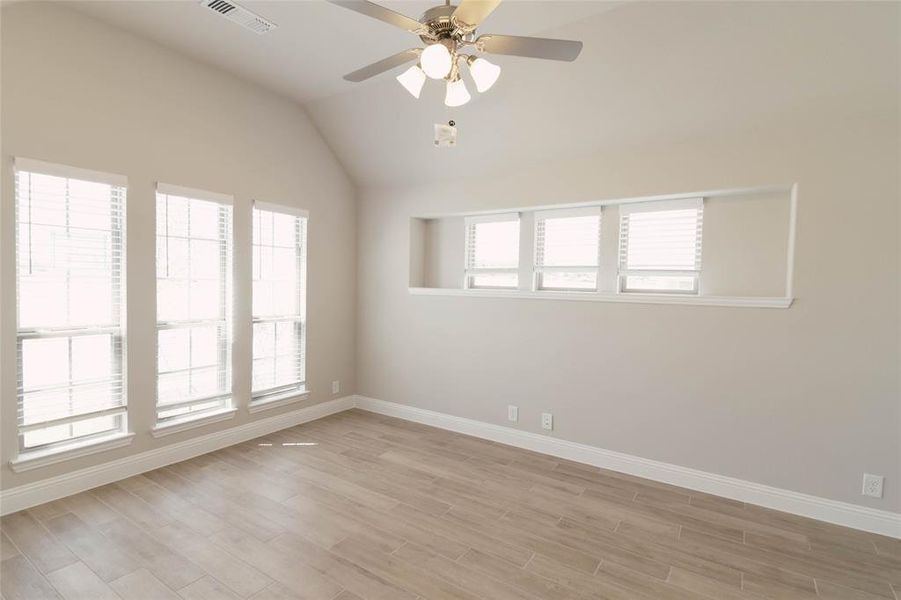 Spare room featuring lofted ceiling, light hardwood / wood-style flooring, and ceiling fan