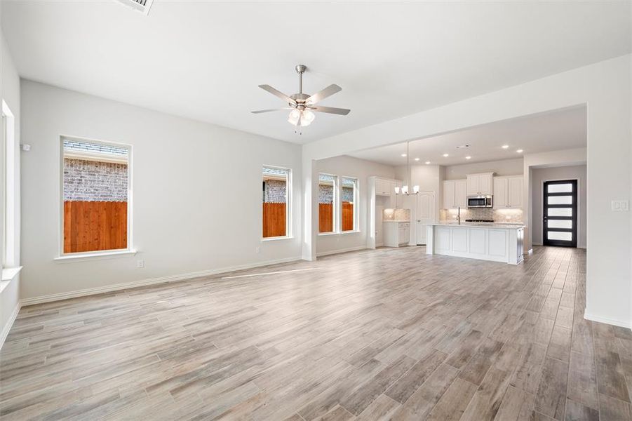 Unfurnished living room featuring recessed lighting, a chandelier, light wood-style floors, healthy amount of natural light, and ceiling fan