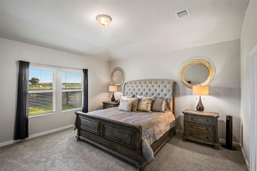 A spacious bedroom with large windows fills the room with natural light, creating a warm and inviting atmosphere.