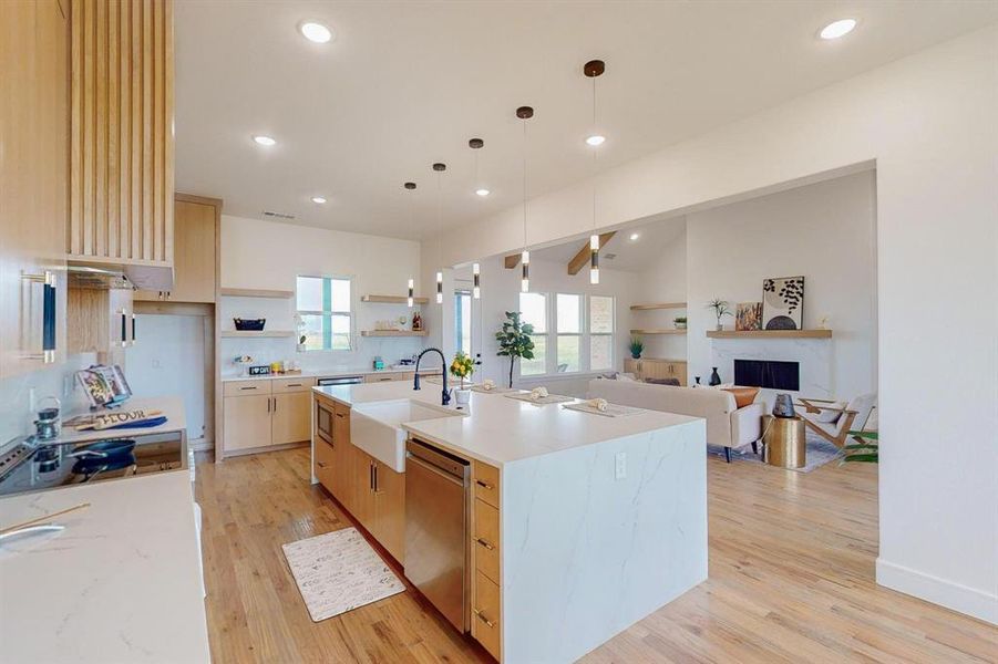 Kitchen with light hardwood / wood-style flooring, a wealth of natural light, a kitchen island with sink, and sink