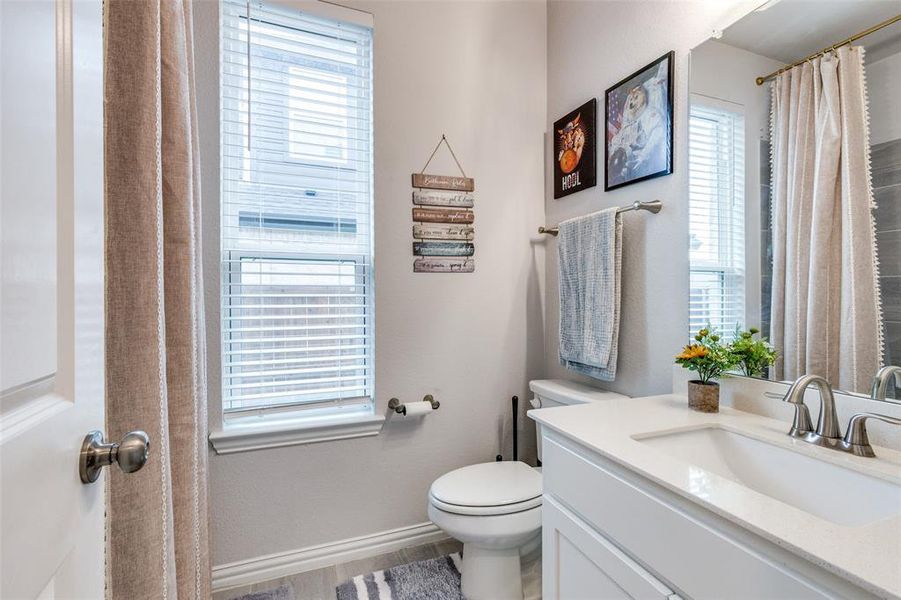 Bathroom featuring a wealth of natural light, toilet, vanity, and hardwood / wood-style flooring