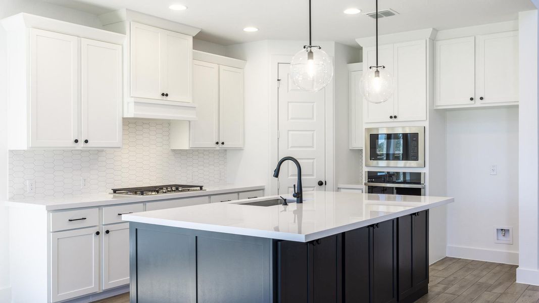 Kitchen featuring backsplash, white cabinets, an island with sink, and recessed lighting