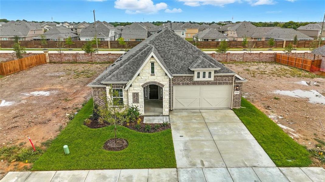 French country inspired facade featuring roof with shingles, stone siding, driveway, a garage, and a fenced backyard French country inspired facade featuring roof with shingles, stone siding, driveway, a garage, and a fenced backyard