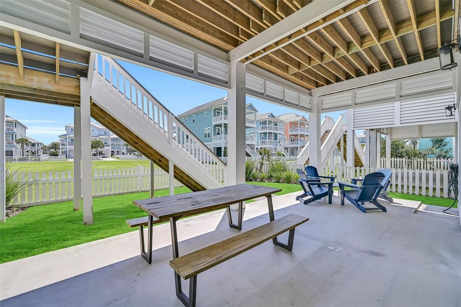 This covered ground level setup delivers the kind of flexible entertaining space that makes coastal homes truly unforgettable.  The outdoor shower is just off to the right.