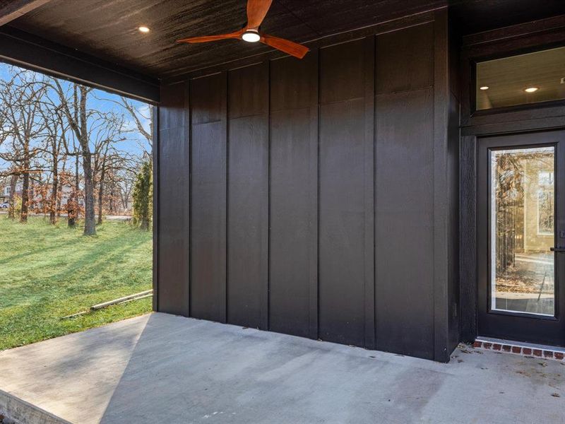 View of exterior entry featuring a patio area, a ceiling fan, a yard, and board and batten siding View of exterior entry featuring a patio area, a ceiling fan, a yard, and board and batten siding
