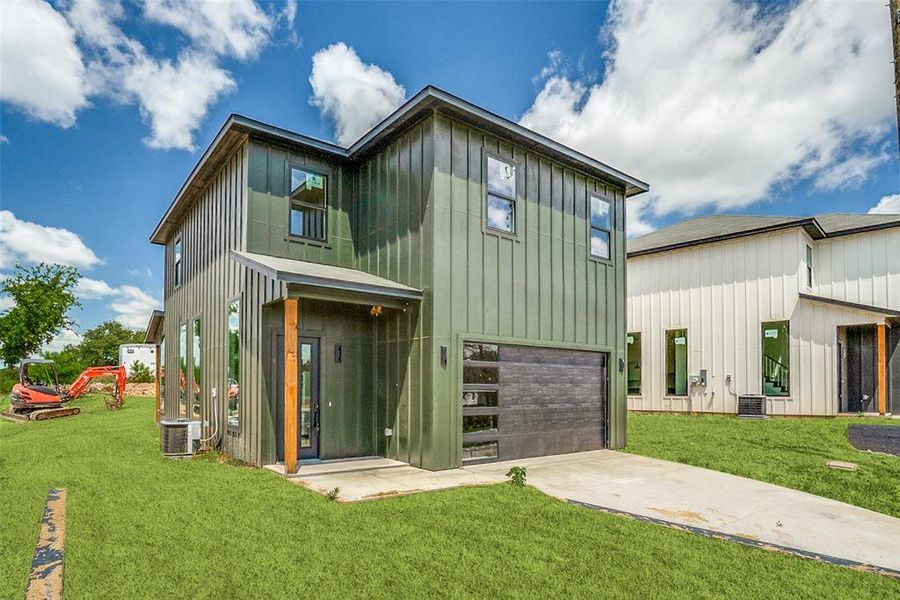 View of front of house featuring driveway, board and batten siding, a garage, and a front lawn