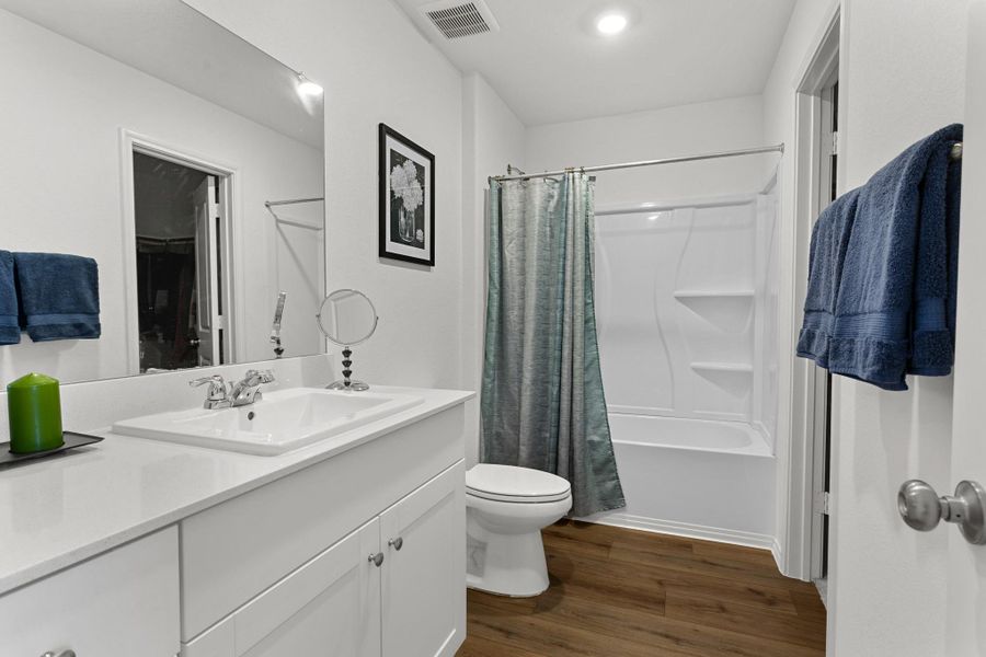 Bathroom featuring a white vanity with an integrated sink, chrome faucet, and expansive wall-mounted mirror
