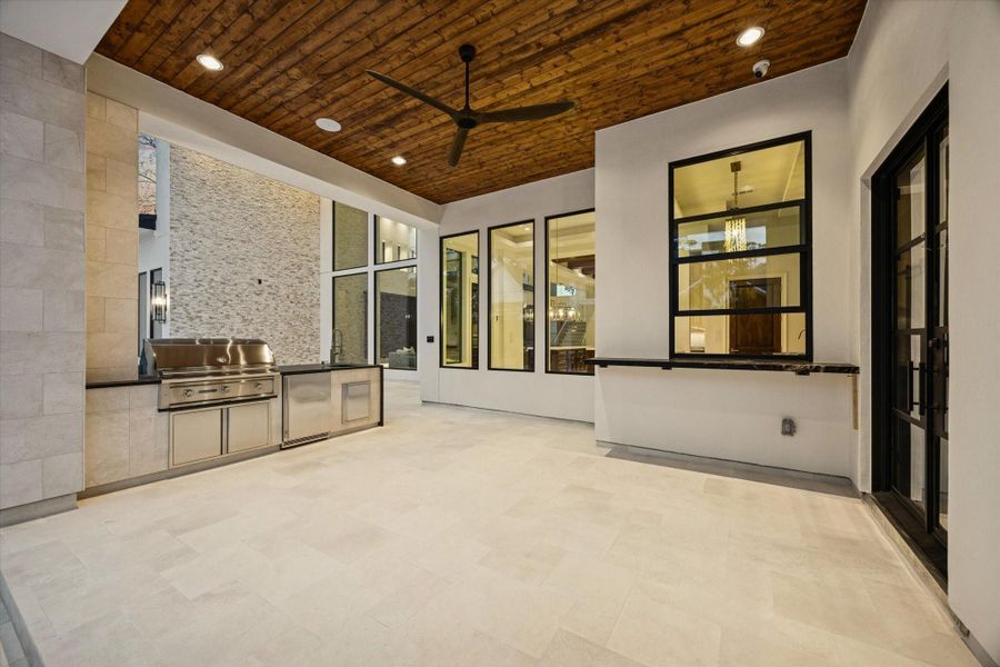 Designed for year-round entertaining, the covered outdoor living area showcases a rich wood-plank ceiling, outdoor BBQ, and a plass-through serving window, creating the ultimate indoor-outdoor lifestyle. Designed for year-round entertaining, the covered outdoor living area showcases a rich wood-plank ceiling, outdoor BBQ, and a plass-through serving window, creating the ultimate indoor-outdoor lifestyle.