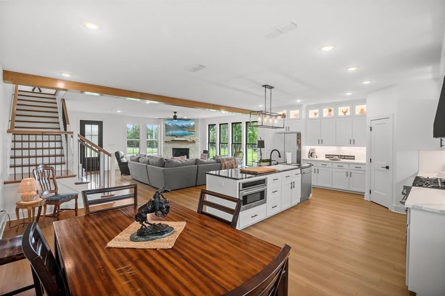Dining space featuring recessed lighting, stairway, light wood finished floors, a fireplace, and a chandelier Dining space featuring recessed lighting, stairway, light wood finished floors, a fireplace, and a chandelier