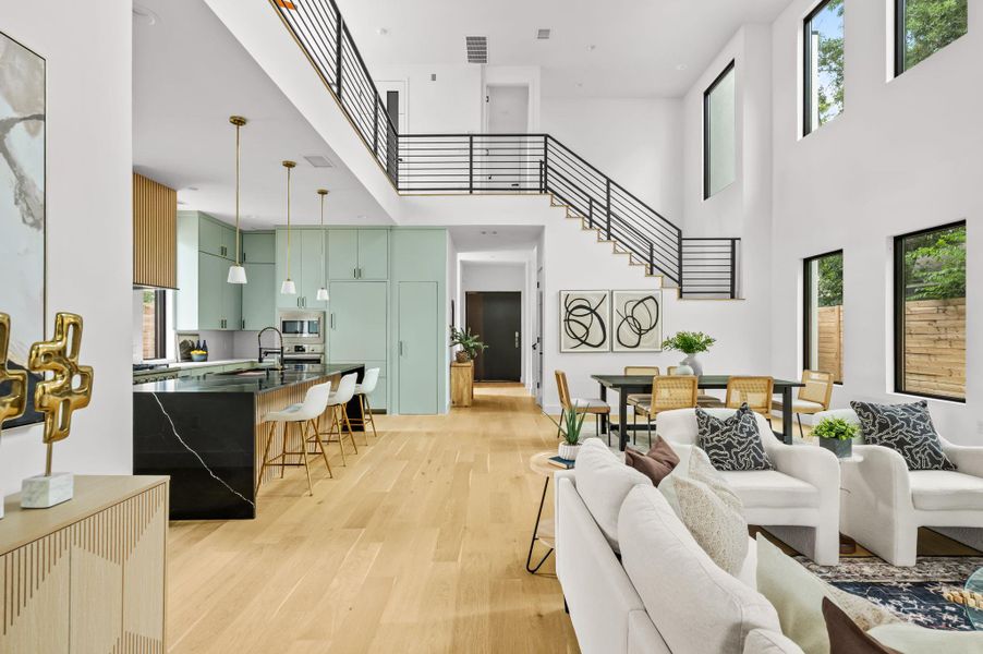 An open-concept living space presents a modern kitchen, a dining area, and a grand staircase connecting the levels. An open-concept living space presents a modern kitchen, a dining area, and a grand staircase connecting the levels.