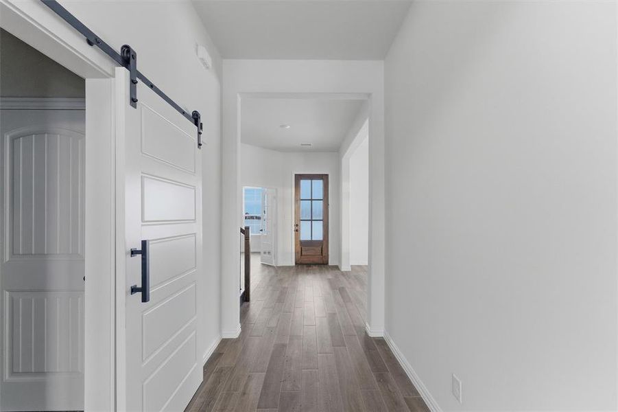 Hall with a barn door and dark wood-style flooring