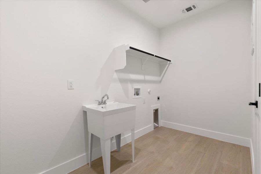 Washroom with light wood-type flooring, gas dryer hookup, electric dryer hookup, and washer hookup Washroom with light wood-type flooring, gas dryer hookup, electric dryer hookup, and washer hookup