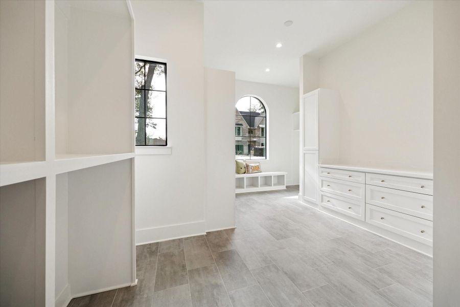 Expansive walk-in closet with custom onsite built-in drawers, open shelving, and a bright window seat area.