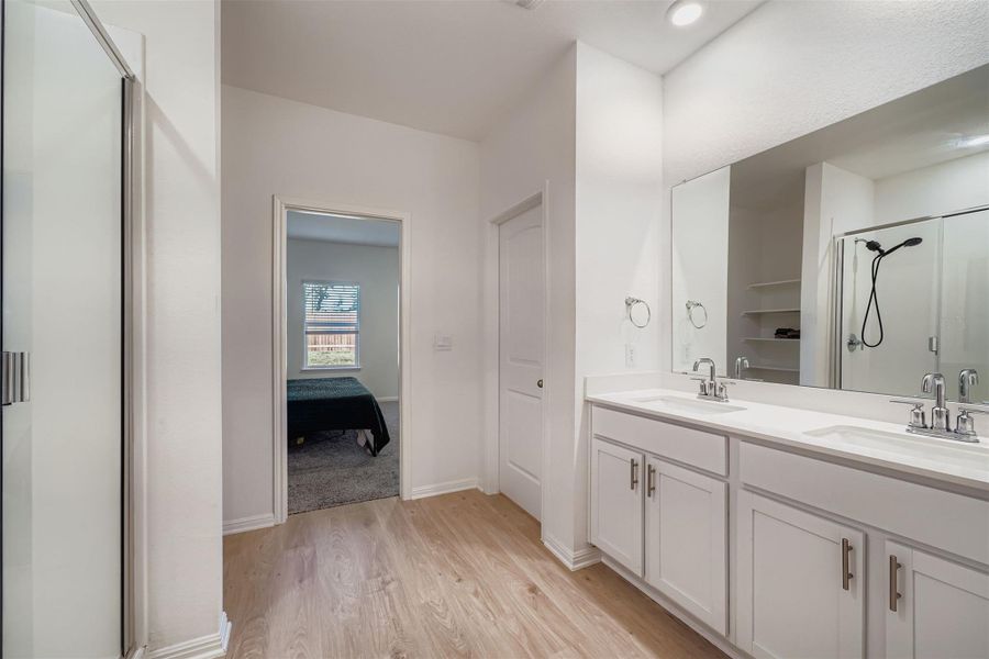 Bathroom with a stall shower, double vanity, light wood-style flooring, and connected bathroom