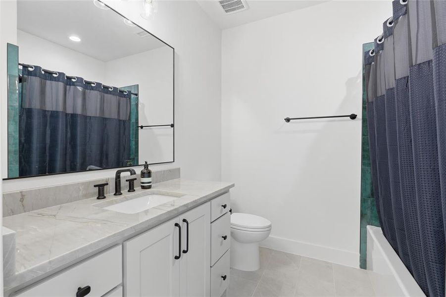 Bathroom featuring a vanity with a light-toned countertop, under-mount sink, and dark-finish faucet