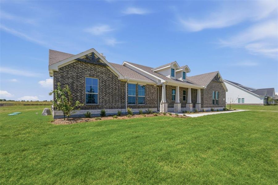 Brick exterior with a gabled roofline, columned front porch, dormer windows, and a manicured lawn Brick exterior with a gabled roofline, columned front porch, dormer windows, and a manicured lawn