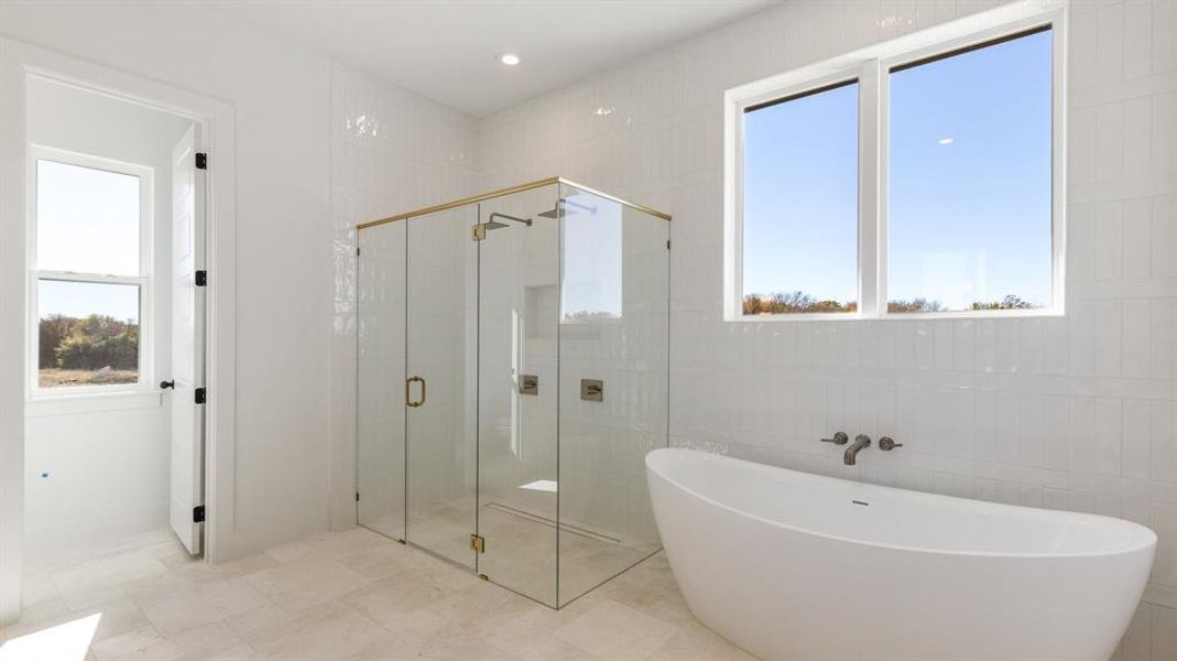 Bathroom featuring a wealth of natural light, tile walls, and shower with separate bathtub