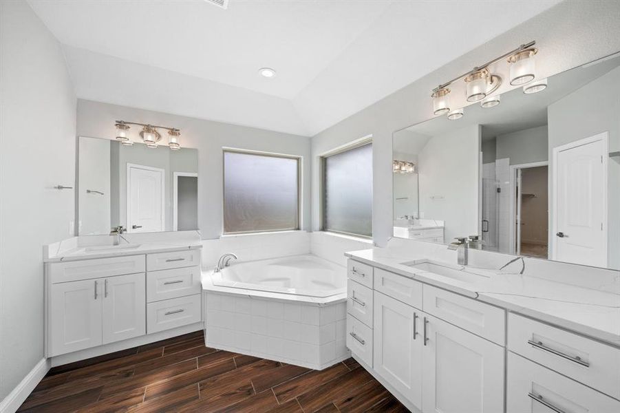 Bathroom with plus walk in shower, vaulted ceiling, hardwood / wood-style floors, and dual bowl vanity