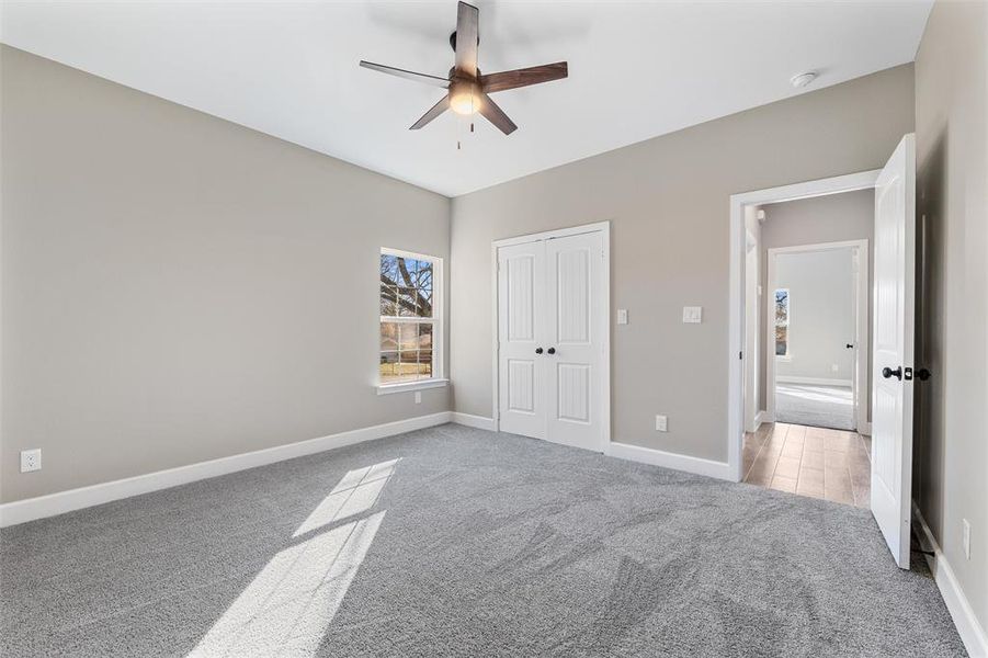 Unfurnished bedroom featuring ceiling fan, a closet, and light carpet