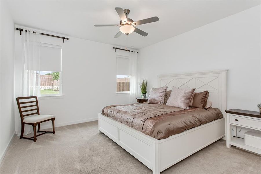 This room features light-colored carpeting, white walls, and a ceiling fan with an integrated light fixture