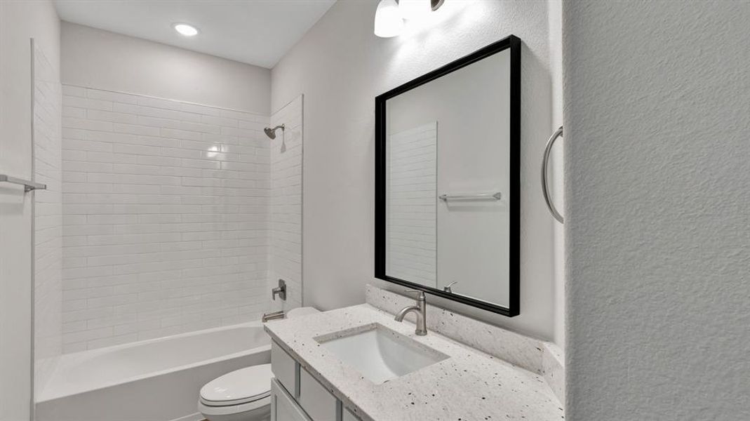 Full bathroom featuring vanity, tiled shower / bath, and toilet