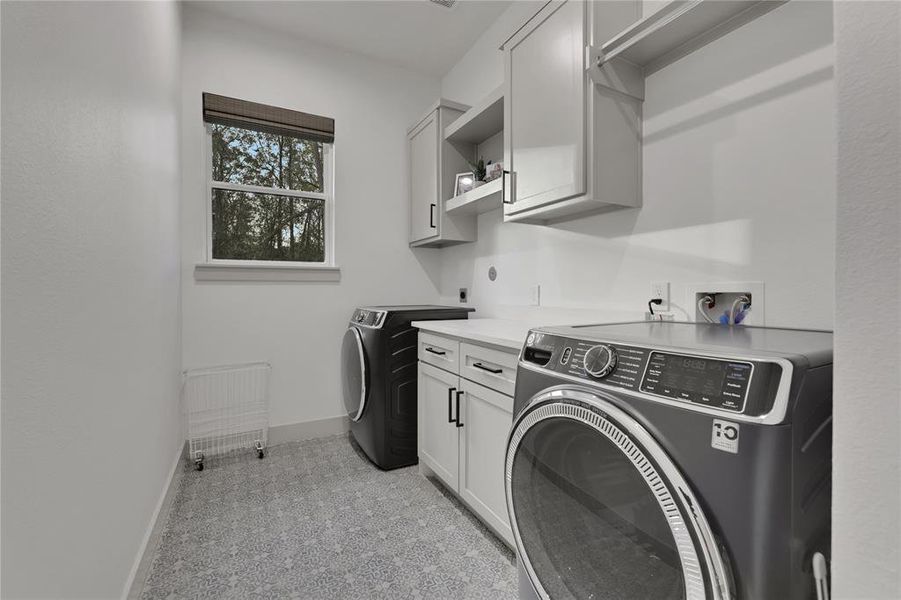 Spacious utility room with cabinets for storage and folding area. Washer and dryer are included. Conveniently located just off the kitchen.