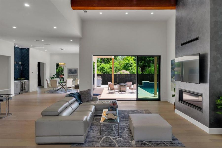 Living room featuring beamed ceiling, a towering ceiling, and light hardwood / wood-style flooring