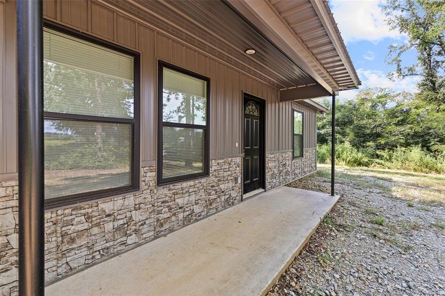 View of exterior entry with stone metal siding and covered porch View of exterior entry with stone metal siding and covered porch