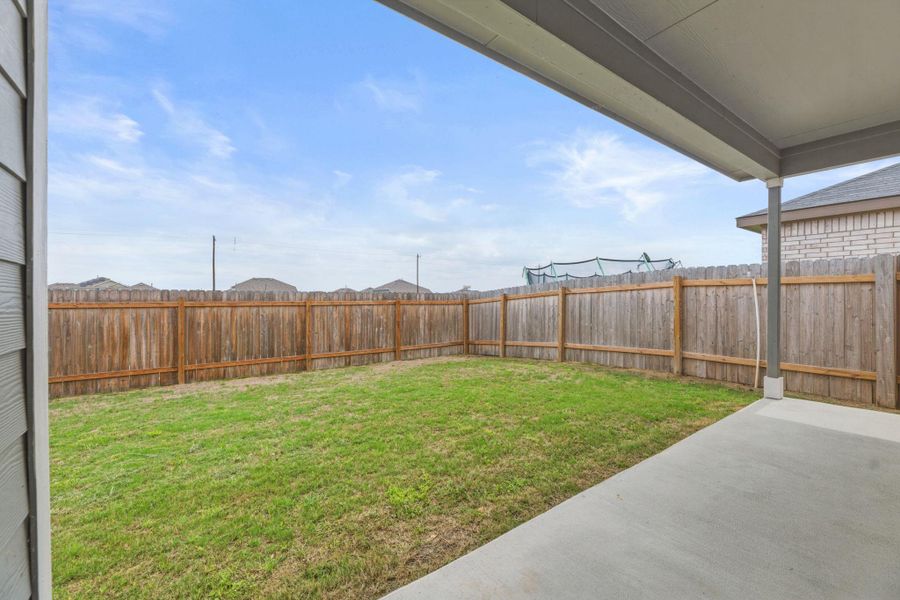 The property features a fenced yard with a manicured lawn and a concrete patio