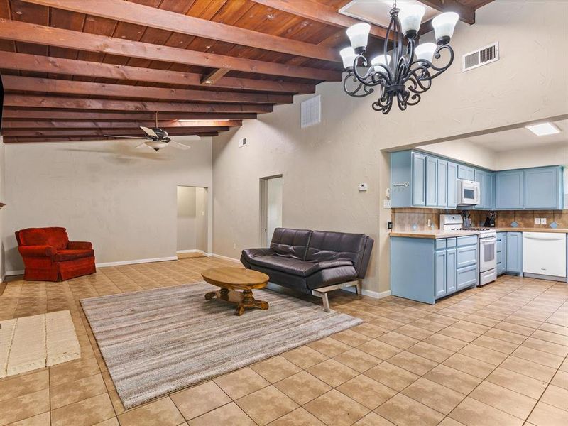 Living area with light tile patterned flooring, a ceiling fan, a wooden ceiling with exposed beams, a chandelier, and a towering ceiling Living area with light tile patterned flooring, a ceiling fan, a wooden ceiling with exposed beams, a chandelier, and a towering ceiling