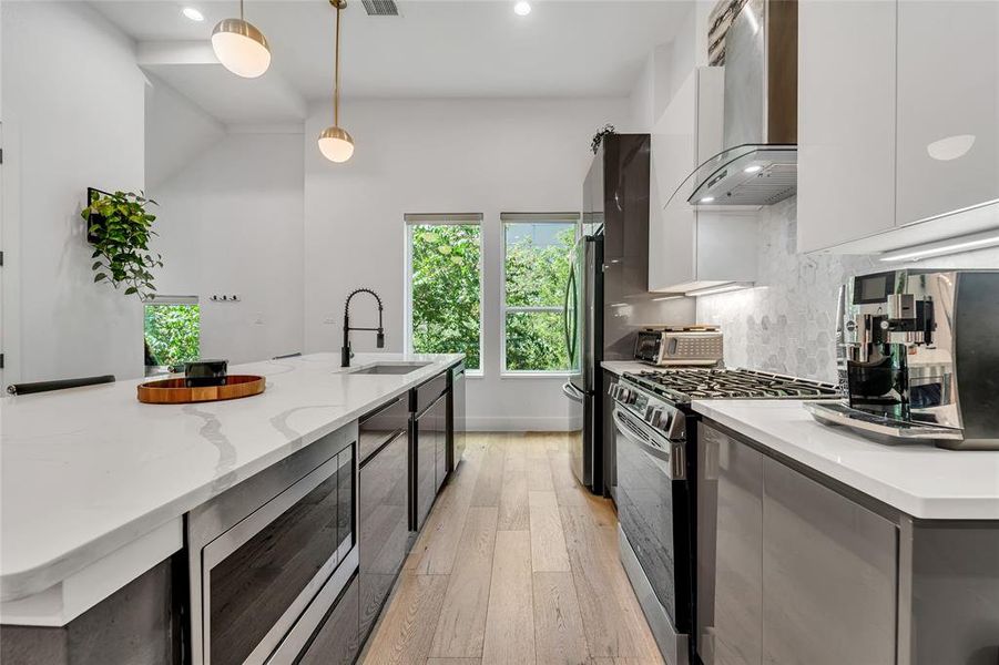 Kitchen with modern cabinets, stainless steel appliances, pendant lighting, light wood-style flooring, and recessed lighting Kitchen with modern cabinets, stainless steel appliances, pendant lighting, light wood-style flooring, and recessed lighting
