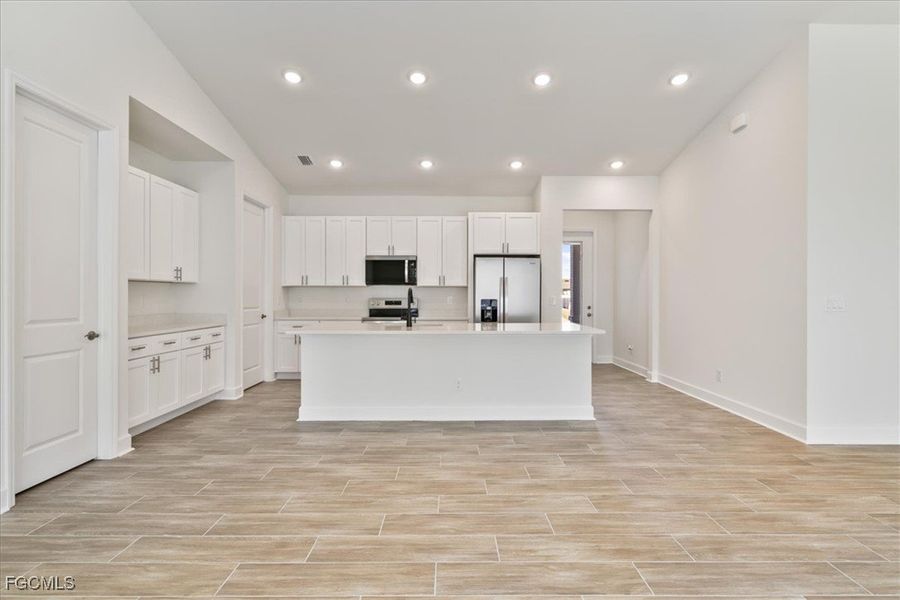 Kitchen featuring white cabinetry, appliances with stainless steel finishes, a kitchen island with sink, recessed lighting, and wood finish floors