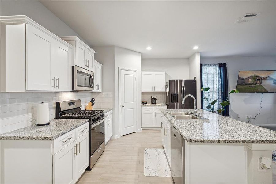 Kitchen with stainless steel appliances, white cabinets, sink, and tasteful backsplash Kitchen with stainless steel appliances, white cabinets, sink, and tasteful backsplash