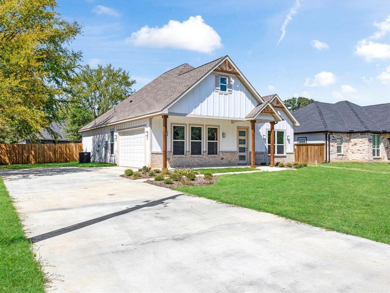 Modern farmhouse style home with brick siding, a porch, concrete driveway, a garage, and board and batten siding Modern farmhouse style home with brick siding, a porch, concrete driveway, a garage, and board and batten siding