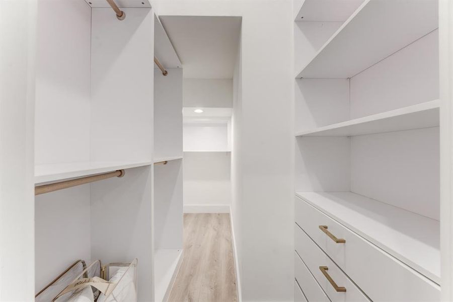 Stunning designer walk-in closet with built in drawers, storage space, and hanging rods for clothes.