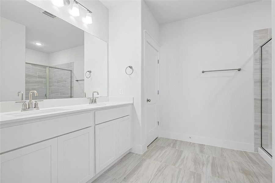 Bathroom featuring a double vanity with white cabinetry and countertops, brushed nickel faucets, and a large mirror