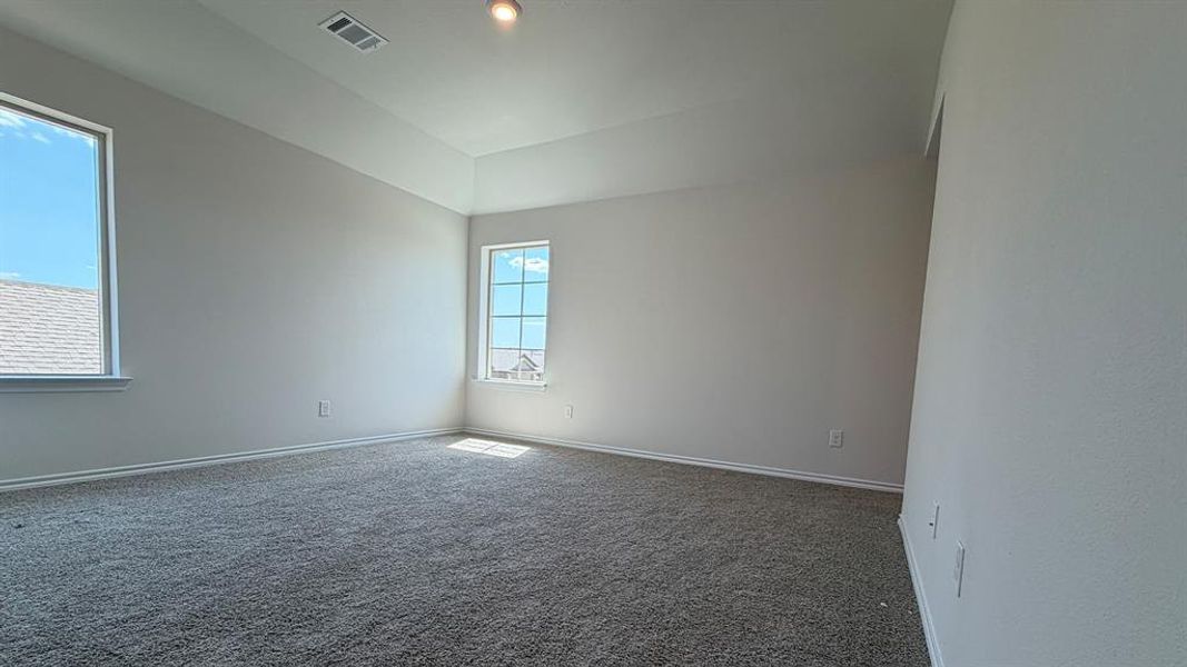 Spacious room featuring neutral carpeting, light-toned walls, and a tray ceiling