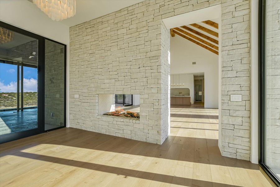 Unfurnished living room with a stone fireplace and wood-type flooring
