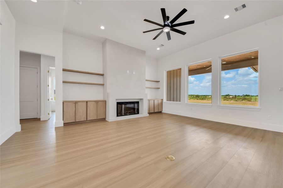 Spacious family room featuring a limewashed fireplace & mantel, built-in cabinetry, and floating shelves. Spacious family room featuring a limewashed fireplace & mantel, built-in cabinetry, and floating shelves.