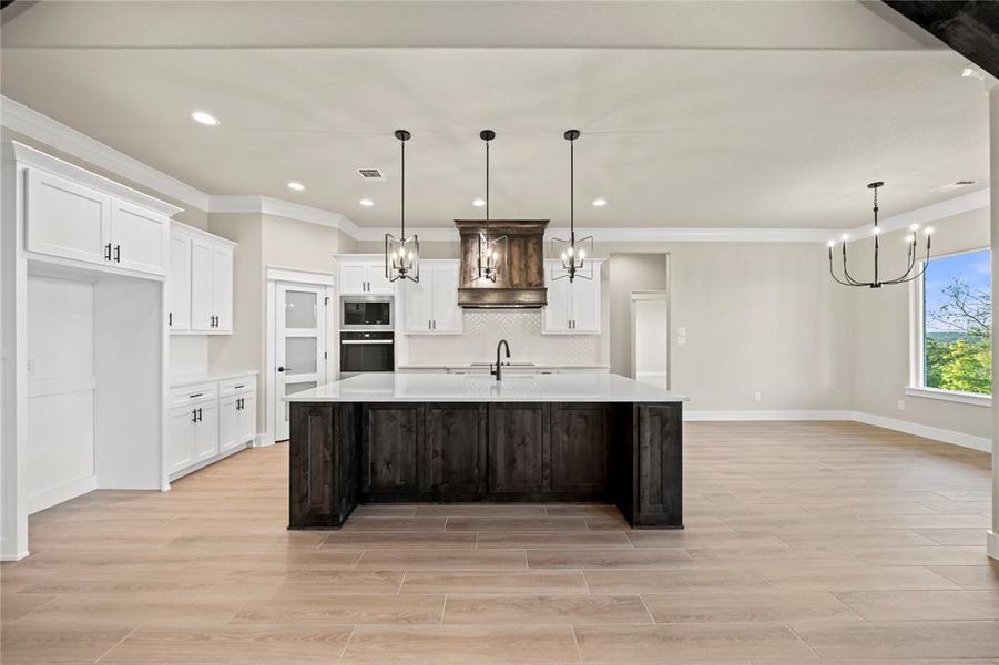 Kitchen featuring white cabinetry, a chandelier, wood finish floors, hanging light fixtures, and recessed lighting
