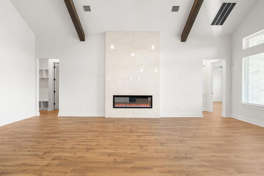 A striking tiled fireplace and warm hardwood floors define this expansive living area.