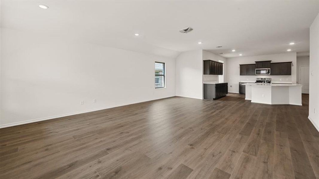 Open-concept living area with wood-finish flooring and recessed lighting Open-concept living area with wood-finish flooring and recessed lighting