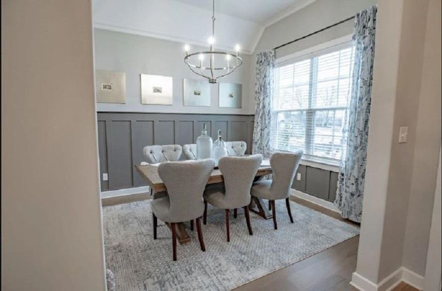 Dining space featuring board and batten wall detailing, wood-finish flooring, and a large window with blinds