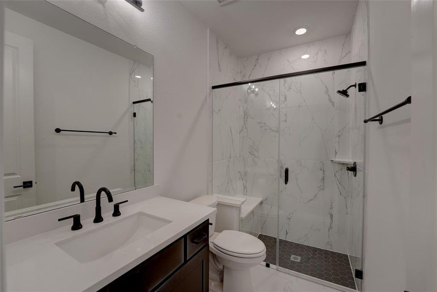 Full bathroom featuring marble finish floor, toilet, vanity, and a marble finish shower