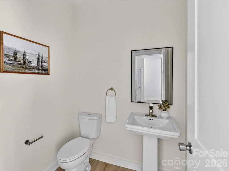 Convenient main-level powder room featuring a pedestal sink, clean finishes, and a bright, modern design. Convenient main-level powder room featuring a pedestal sink, clean finishes, and a bright, modern design.