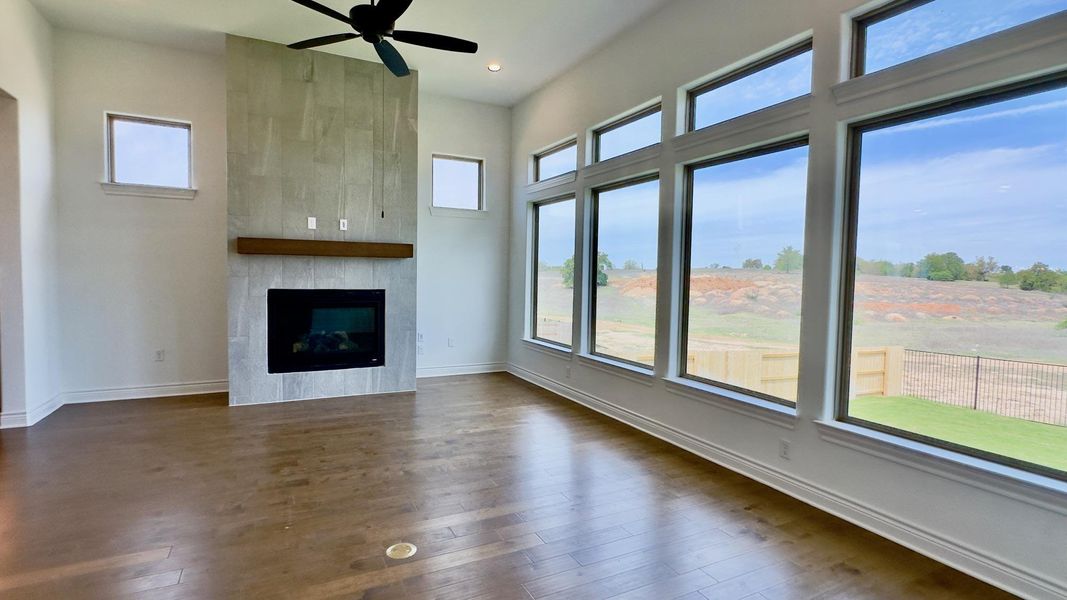 Unfurnished living room with dark wood-type flooring, ceiling fan, and a tile fireplace
