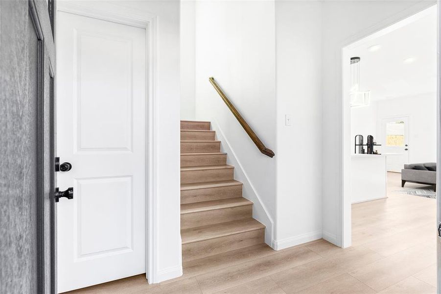 Step into the foyer, where the journey begins with a glimpse of the open living spaces ahead, the stairs leading up, and the conveniently placed half bath tucked away. (Photo may be enhanced and may include virtual staging)