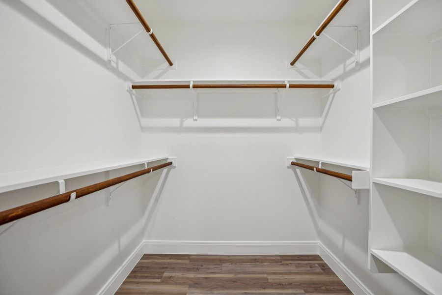 His and Hers Primary Bedroom closets featuring wood finished floors