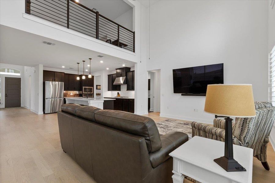 Living room featuring light wood finished floors, a towering ceiling, and plenty of natural light